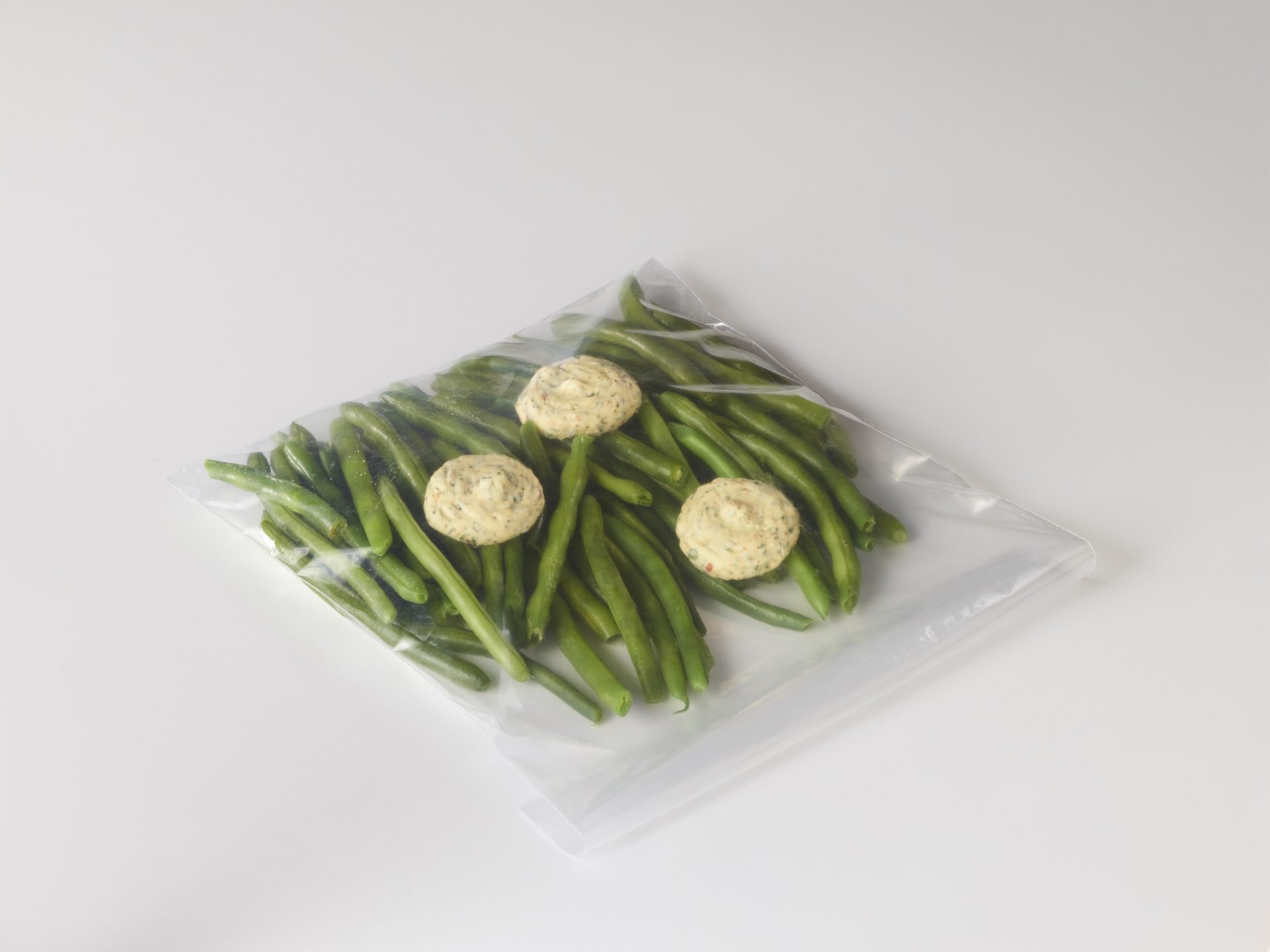 Green beans in a zip lock bag with pats of butter for customer use